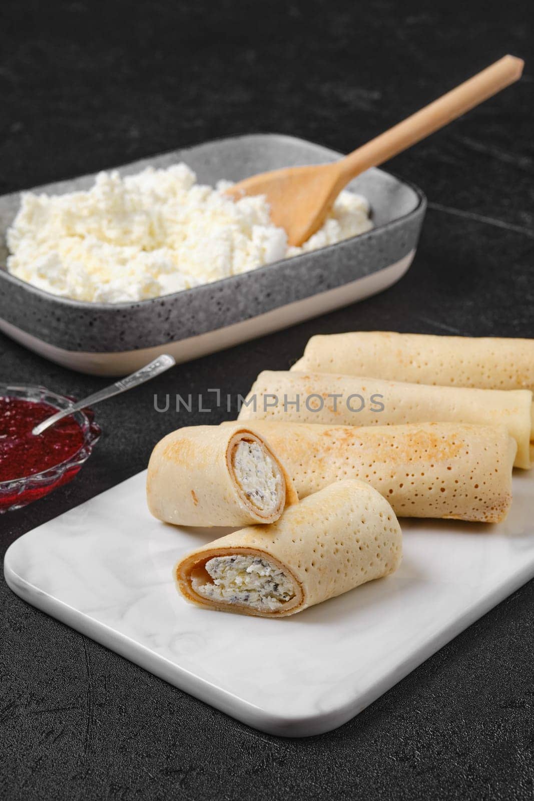 Homemade pancakes stuffed with cottage cheese on marble serving plate