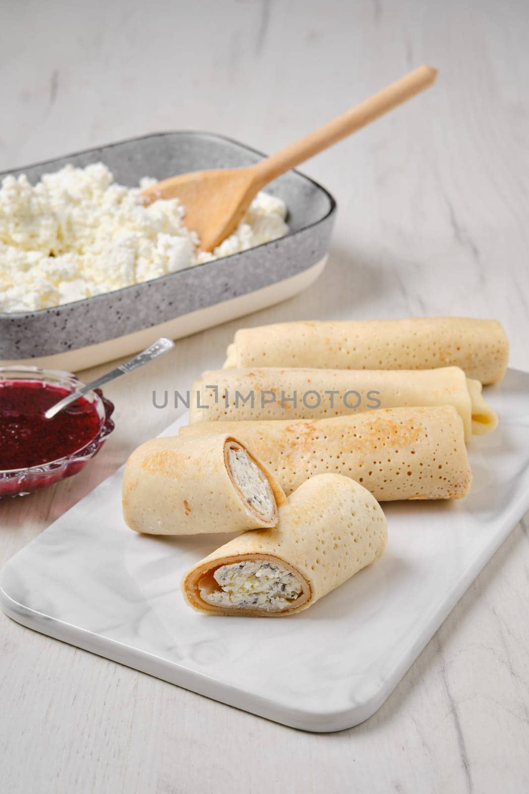 Homemade pancakes stuffed with cottage cheese on marble serving plate
