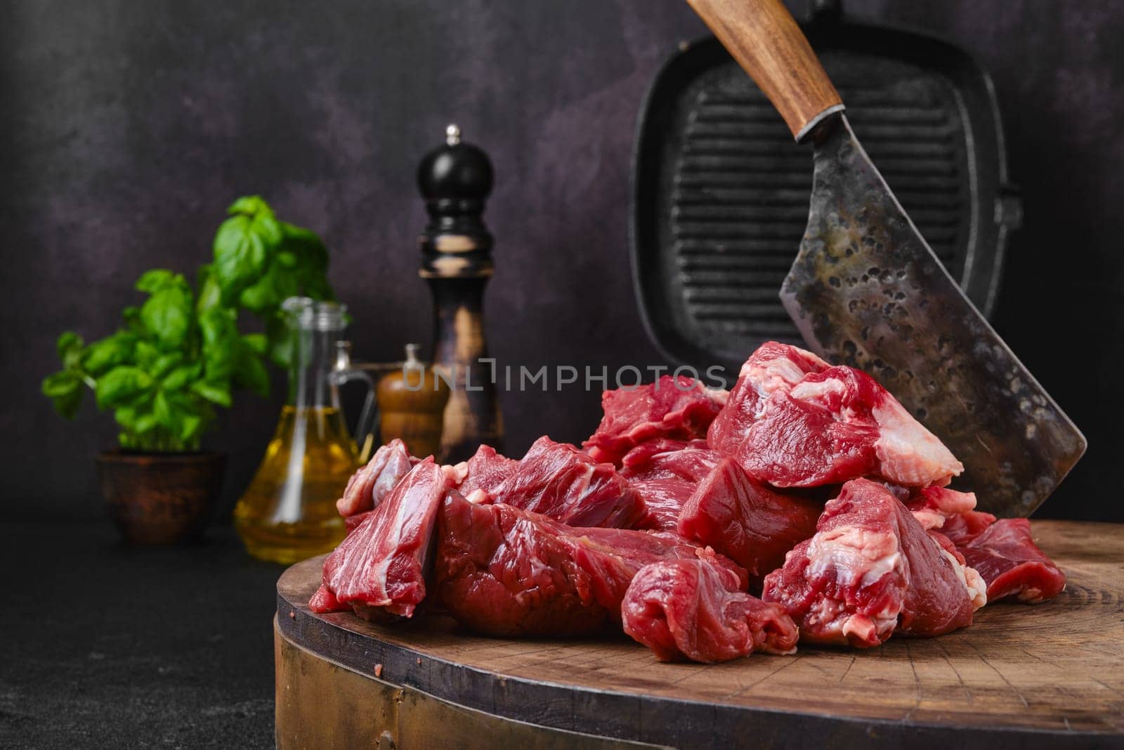 Chopping fresh beef meat for goulash or stew on wooden chopping stump