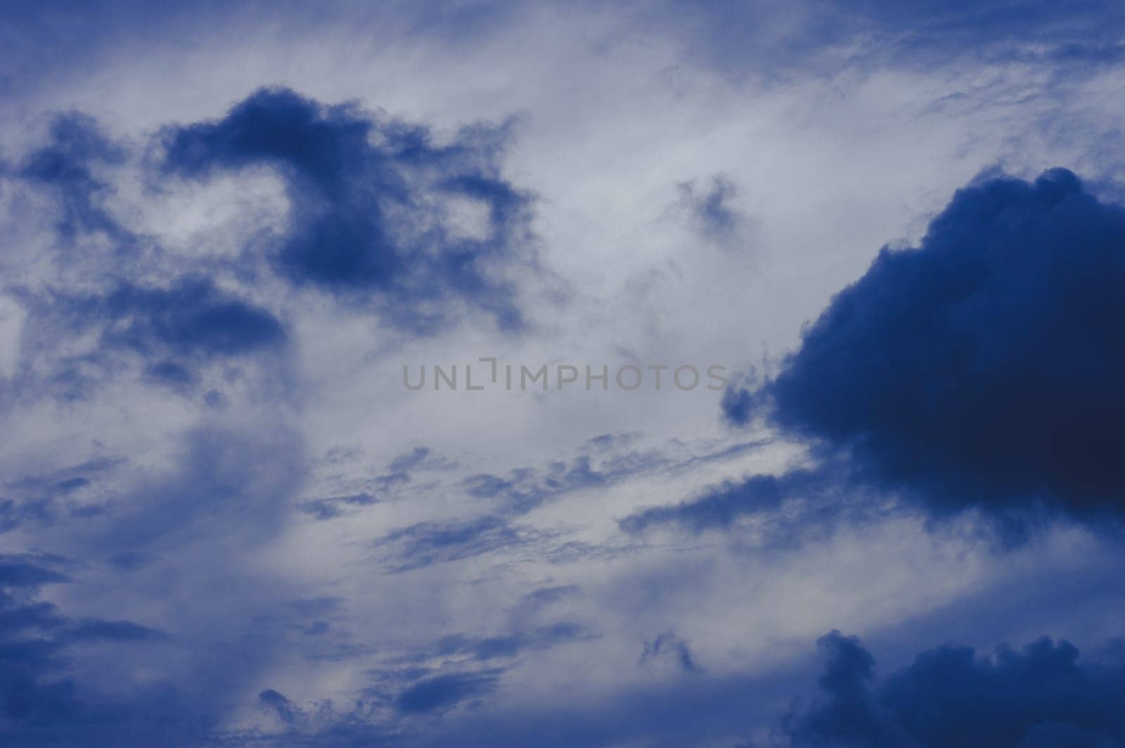 Dark clouds in blue sky background. Dark Rain clouds floating in sunset sky. Nature background.