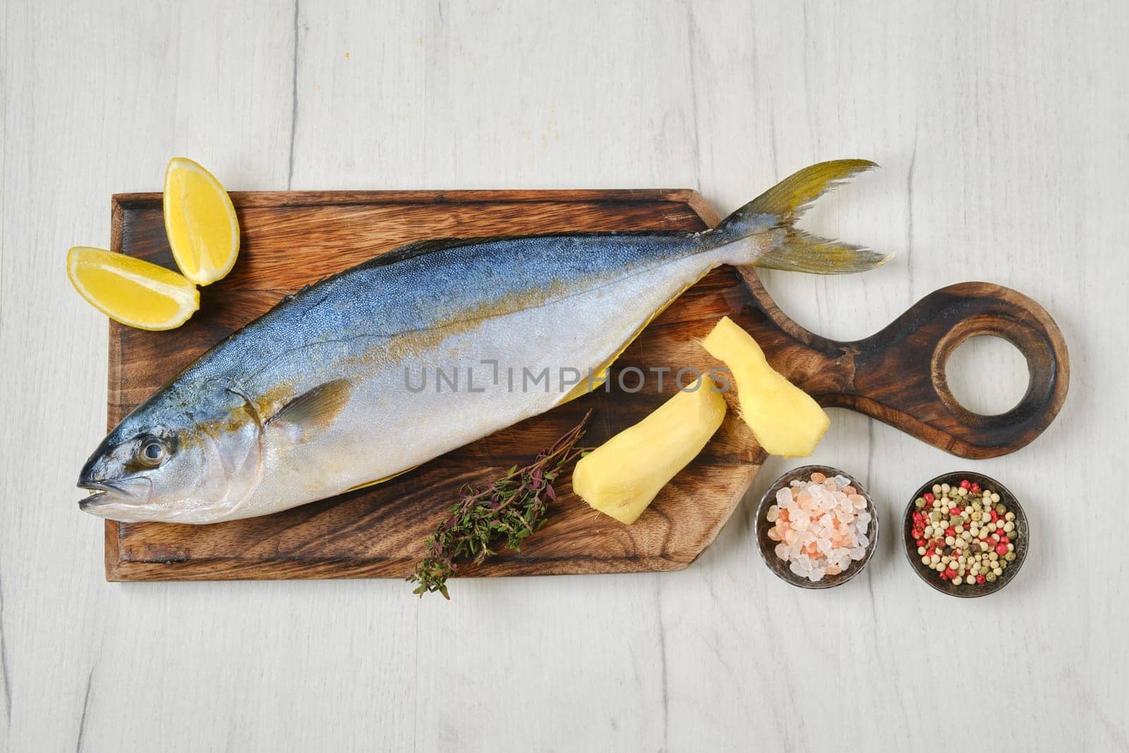 Top view of whole fresh chinook on wooden cutting board with spice, lemon and ginger