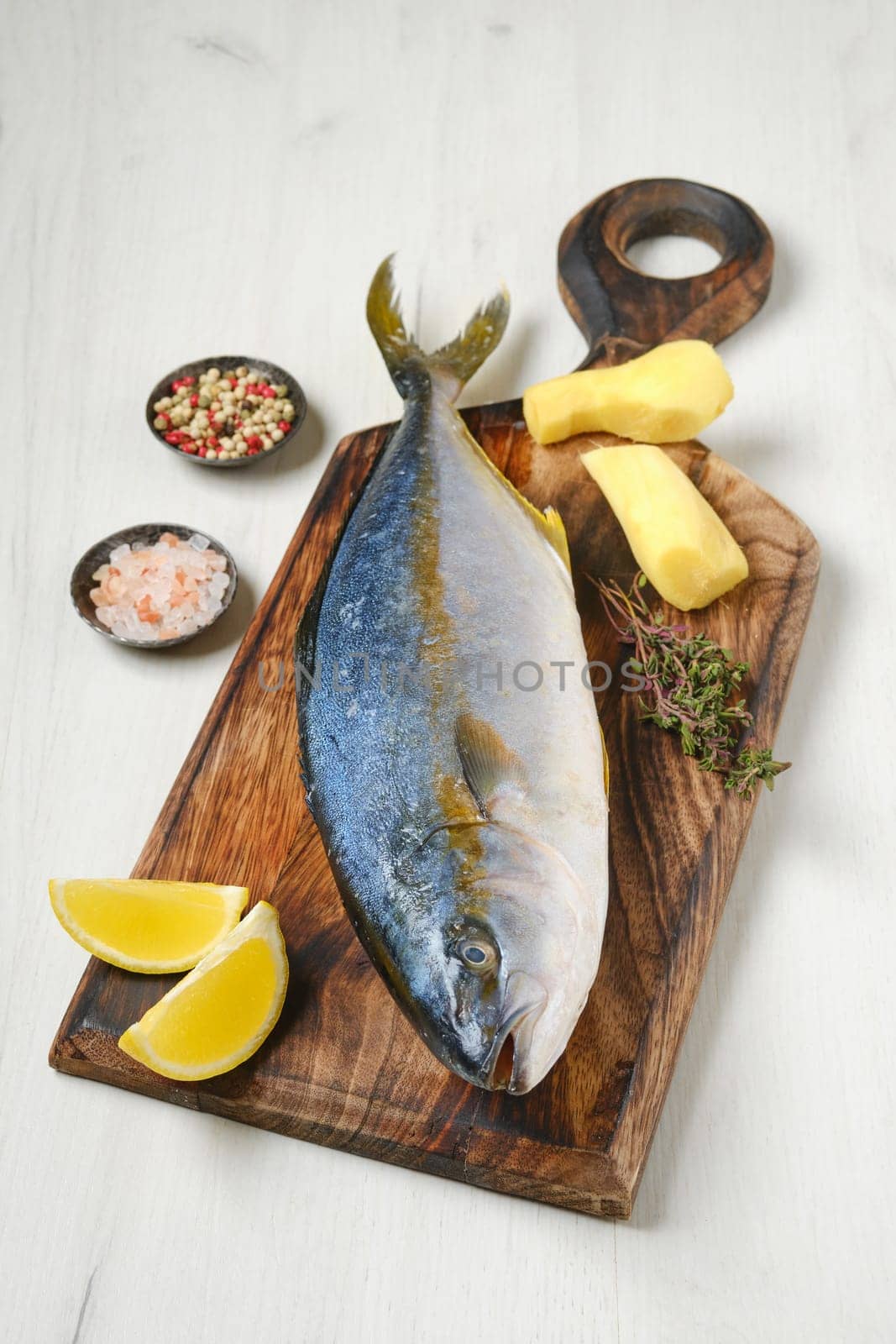 Whole fresh chinook on wooden cutting board with spice, lemon and ginger