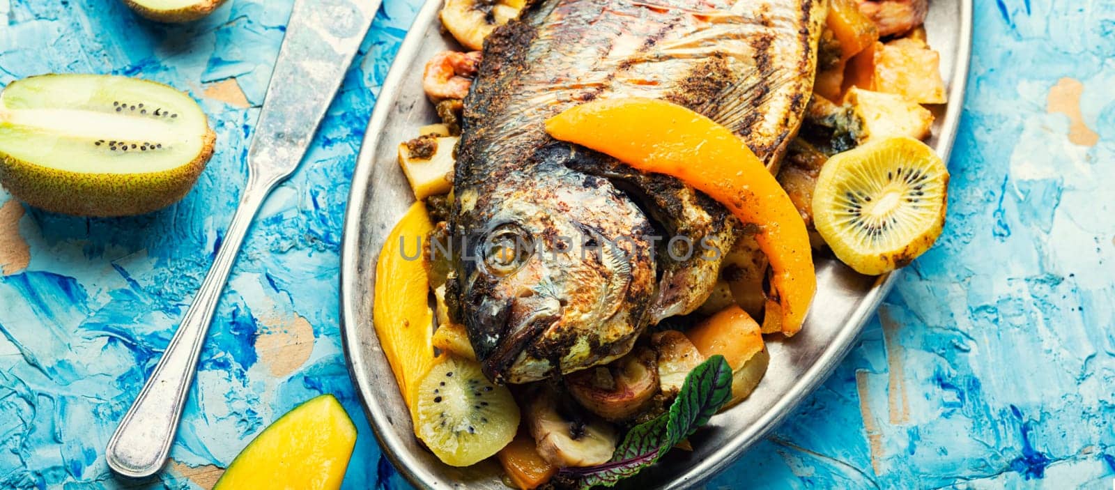 Delicious fried fish dorada with fruits and spices.