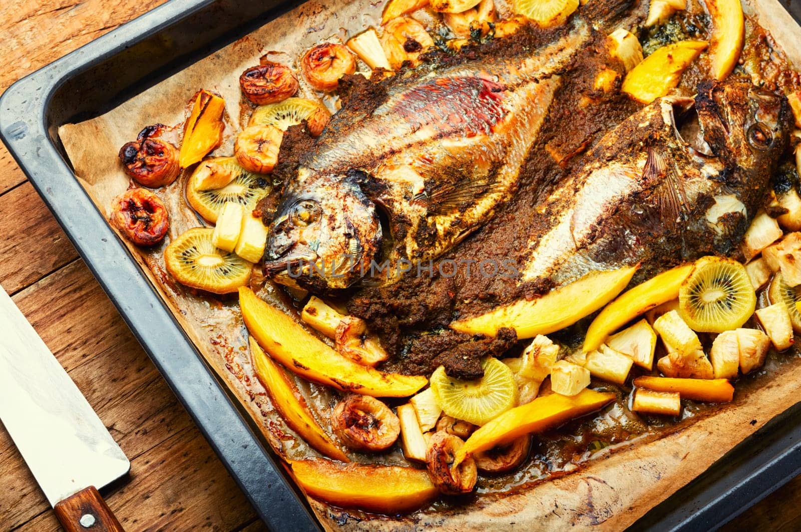 Delicious fried fish dorada with fruits and spices.