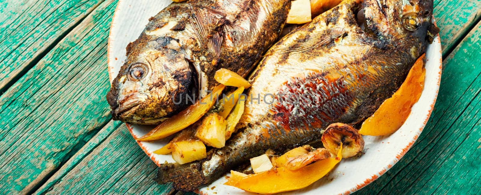 Delicious fried fish dorada with fruits and spices.