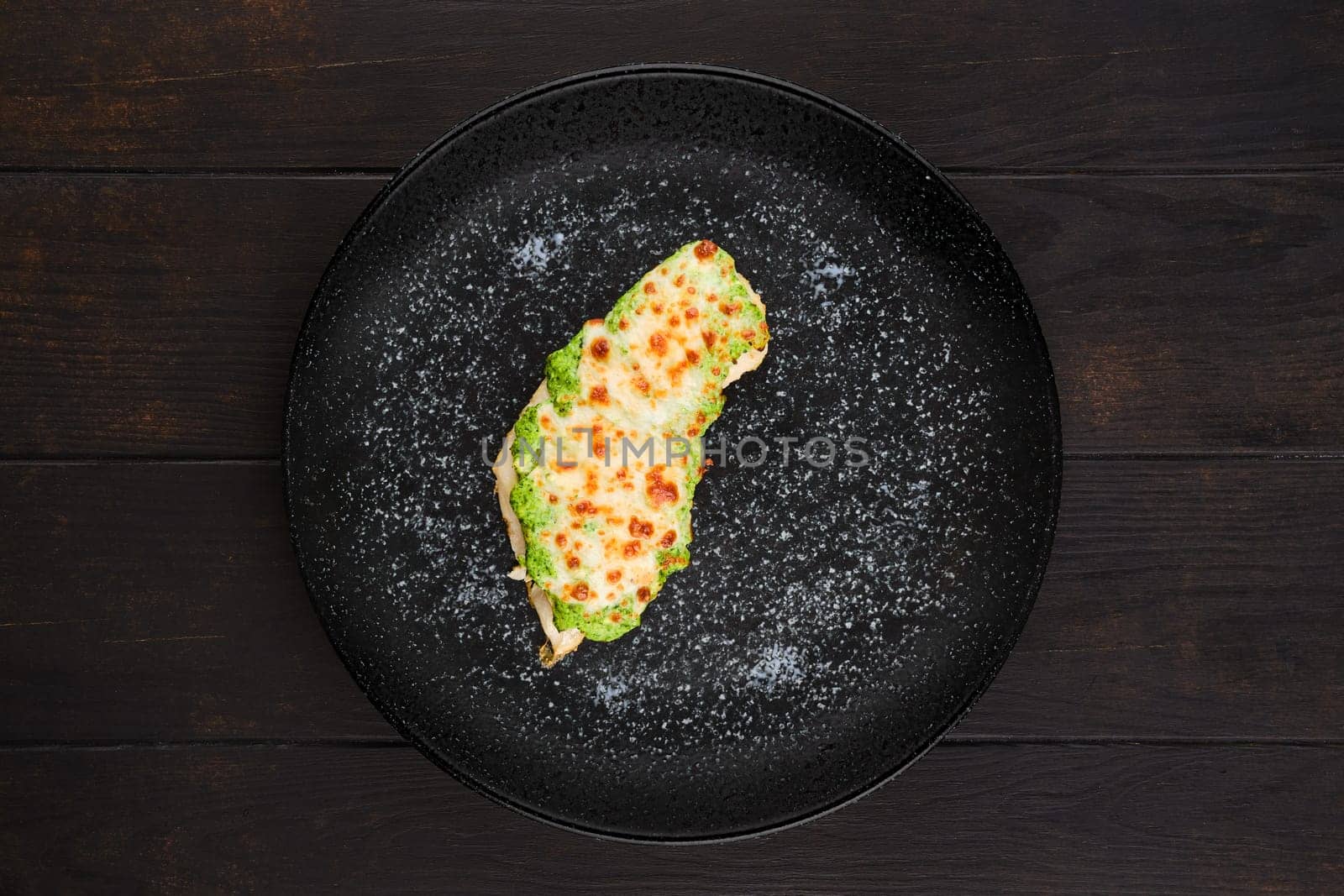 Top view of fried fish fillet with green salsa sauce on a plate