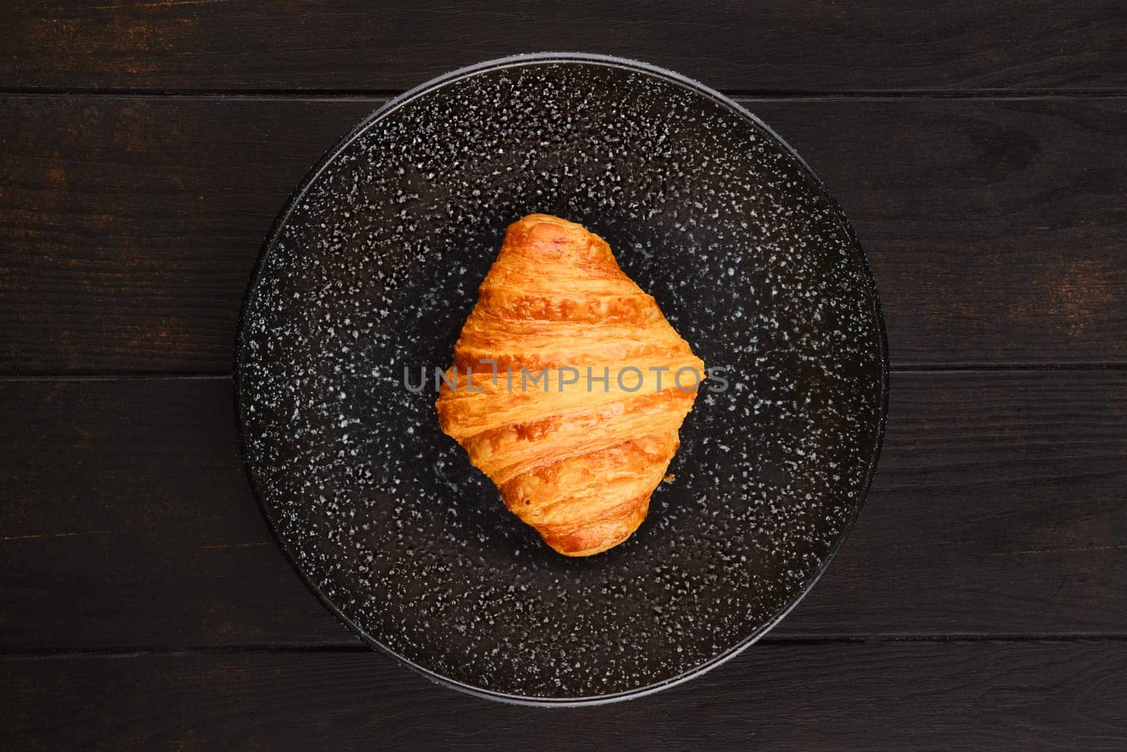 Top view of freshly baked big croissant on a plate