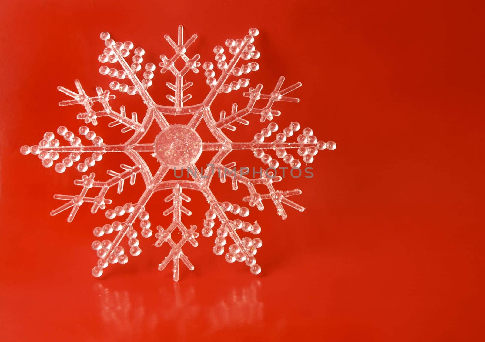 A gluttery snowflake ornament on a red background