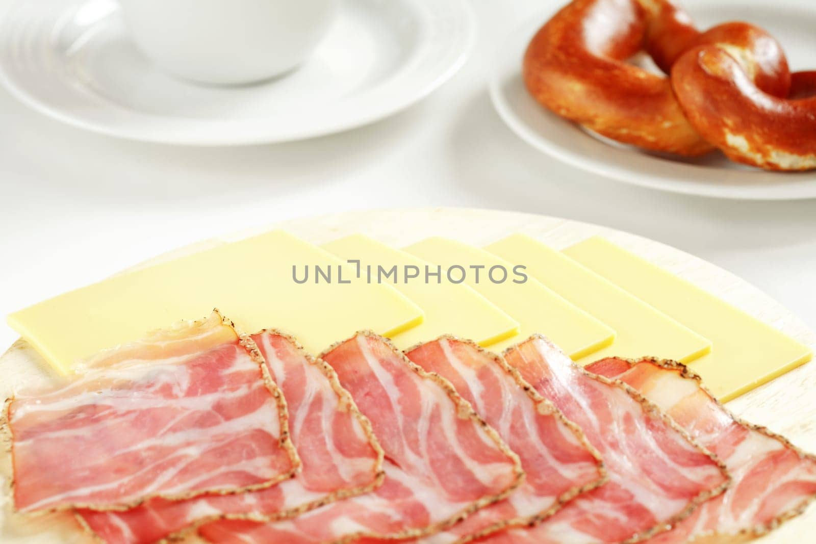 Ham and cheese on wood plate with bread roll and cup
