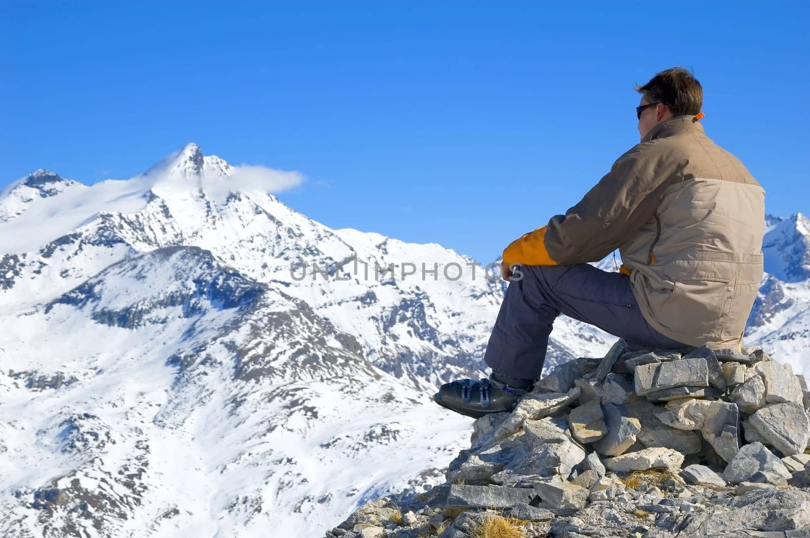 man, sitting on some rocks, looking over a mountain range