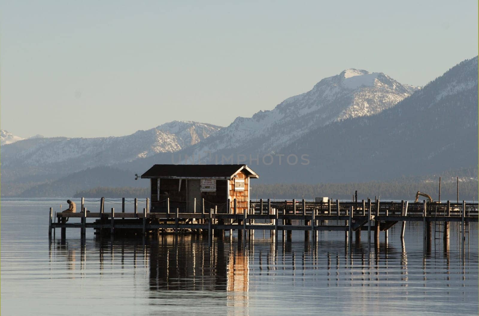Man sitting on a small wooden pier on lake Tahoe, CA