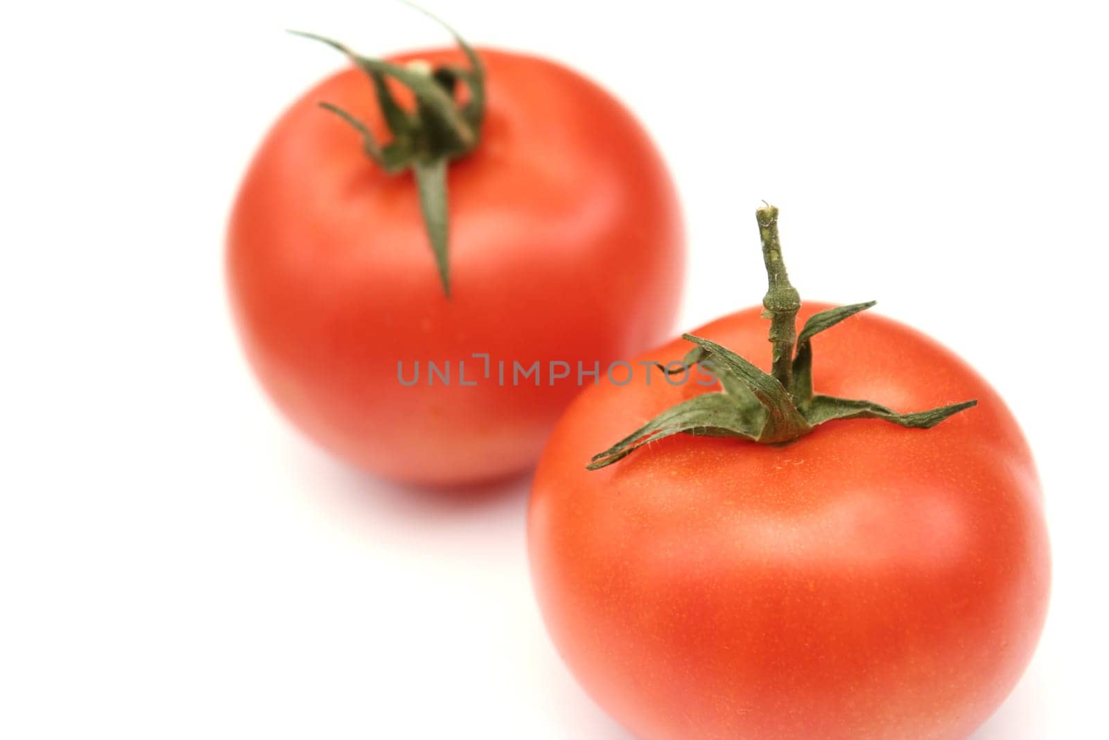 Two red tomatoes lay on a white background