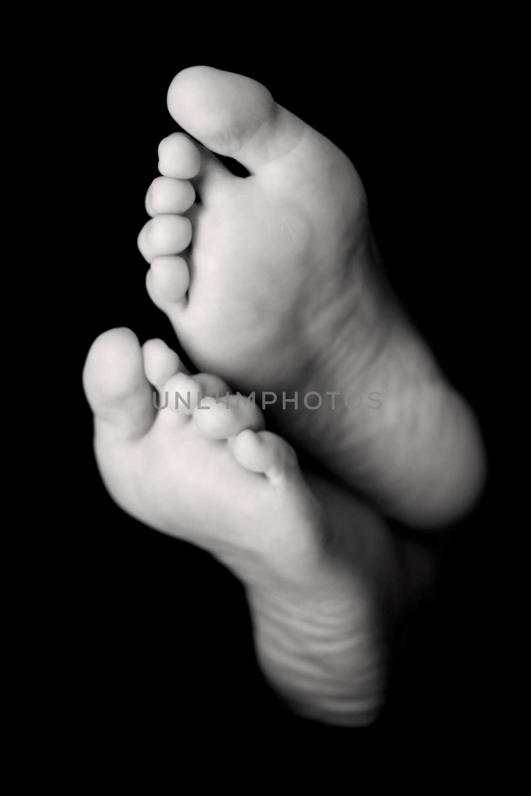 Woman's feet in high key over black. Focus is on the toes of the top foot