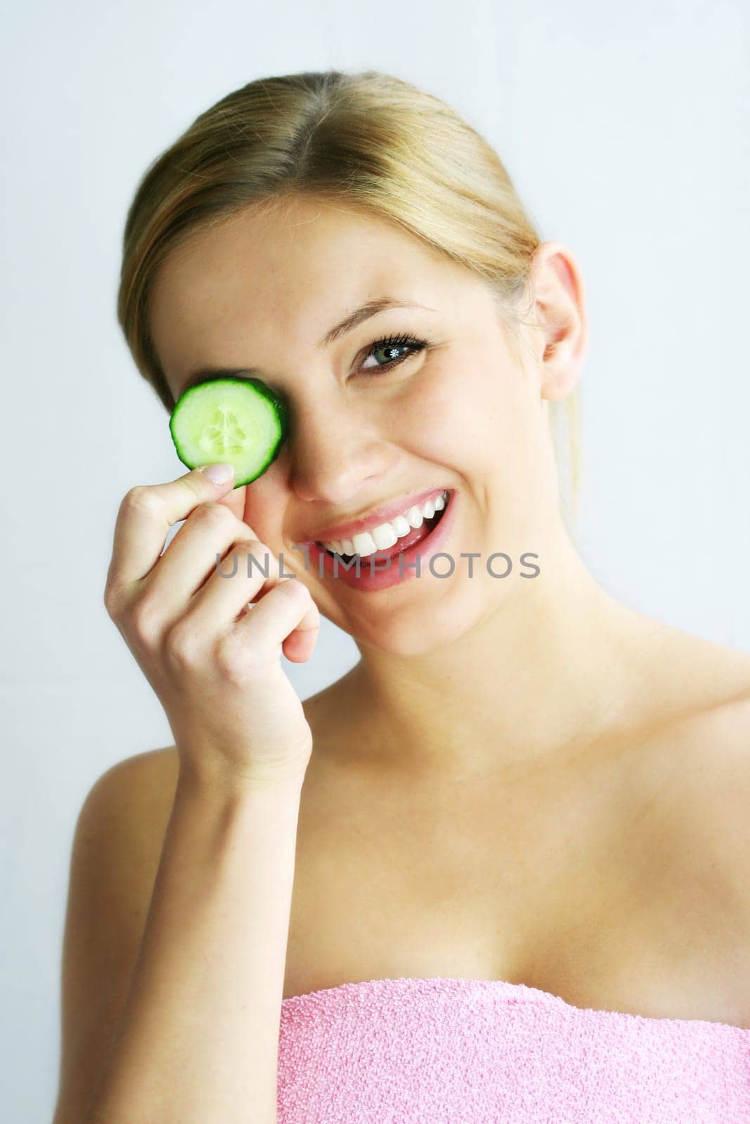 a young, beautiful, happy woman is holding some cucumber in front of her face
