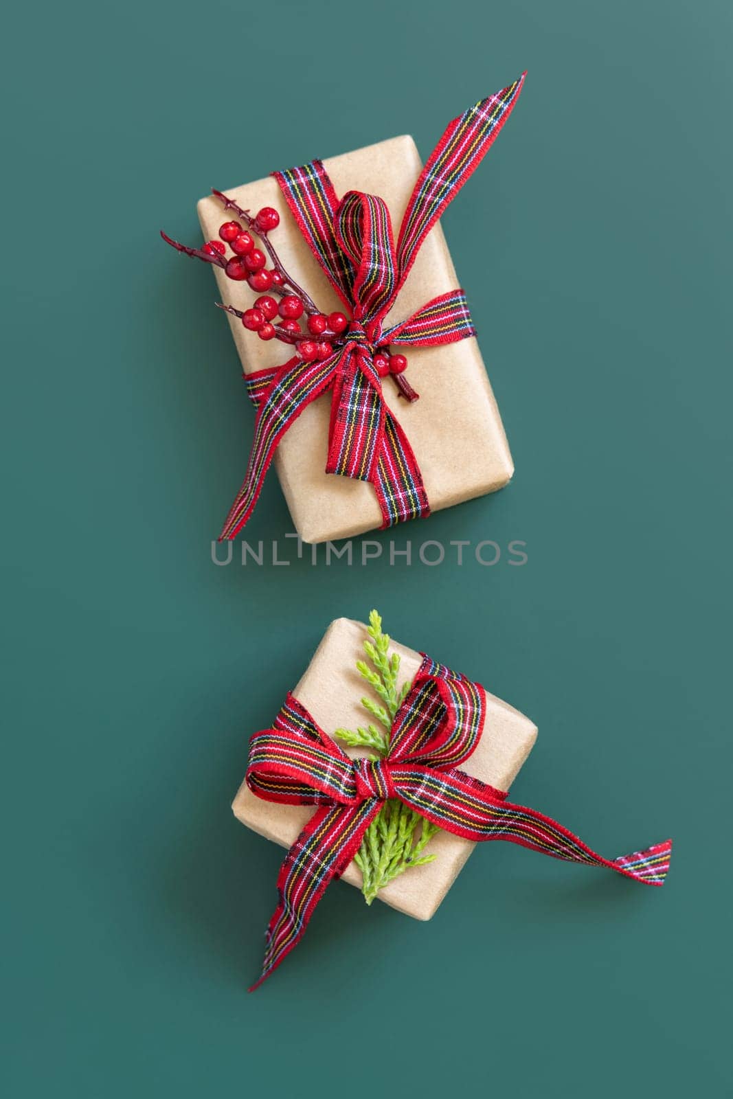 Gift boxes wrapped in karft paper with red ribbon bow on green top view. Christmas or New Year Holiday atmosphere flat lay