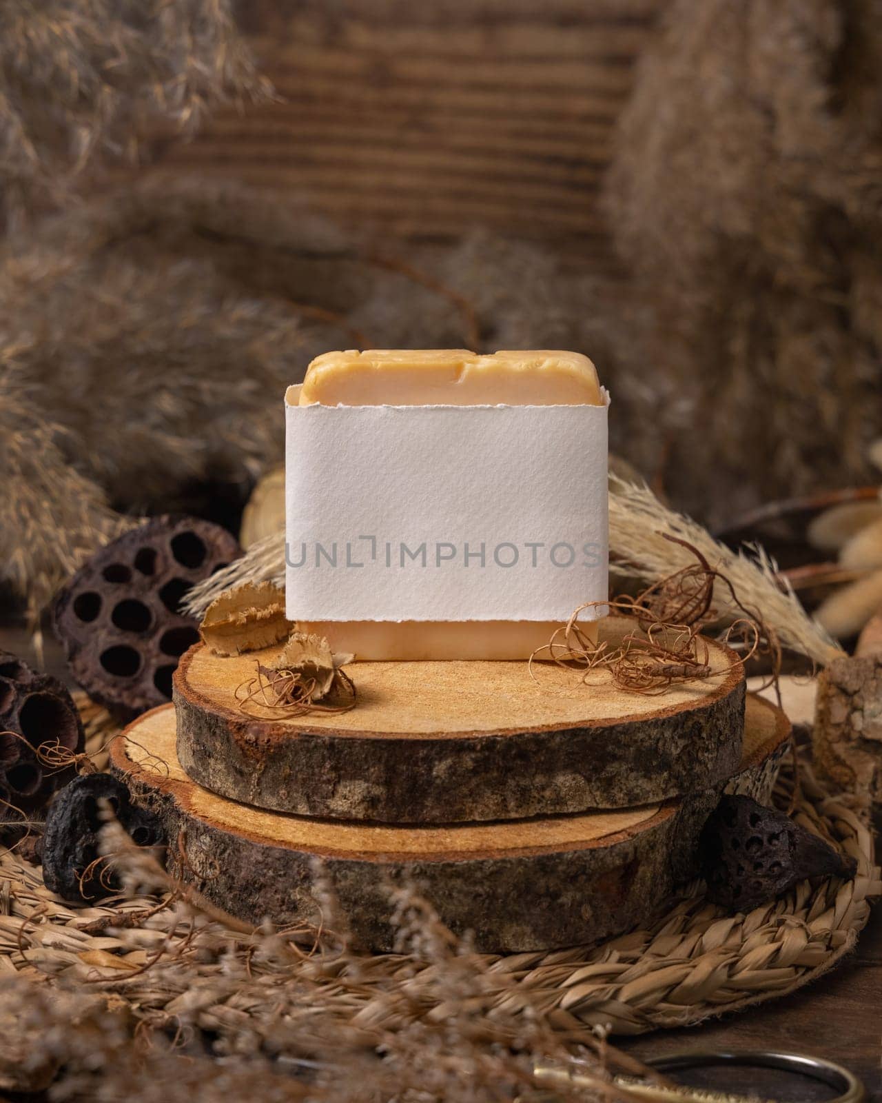 Handmade soap bar with blank label on wood near natural decorations close up, package mockup. Eco friendly skincare product. Bohemian composition with dried leaves and flowers.