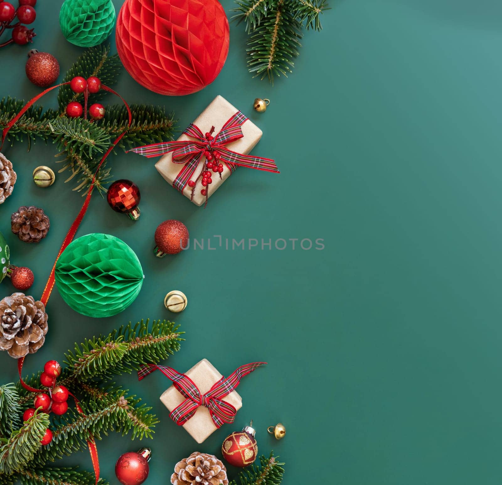 Border made of Wrapped gift boxes, Christmas decorations and green fir branches top view on green background, copy space. Christmas or New Year Holiday atmosphere flat lay
