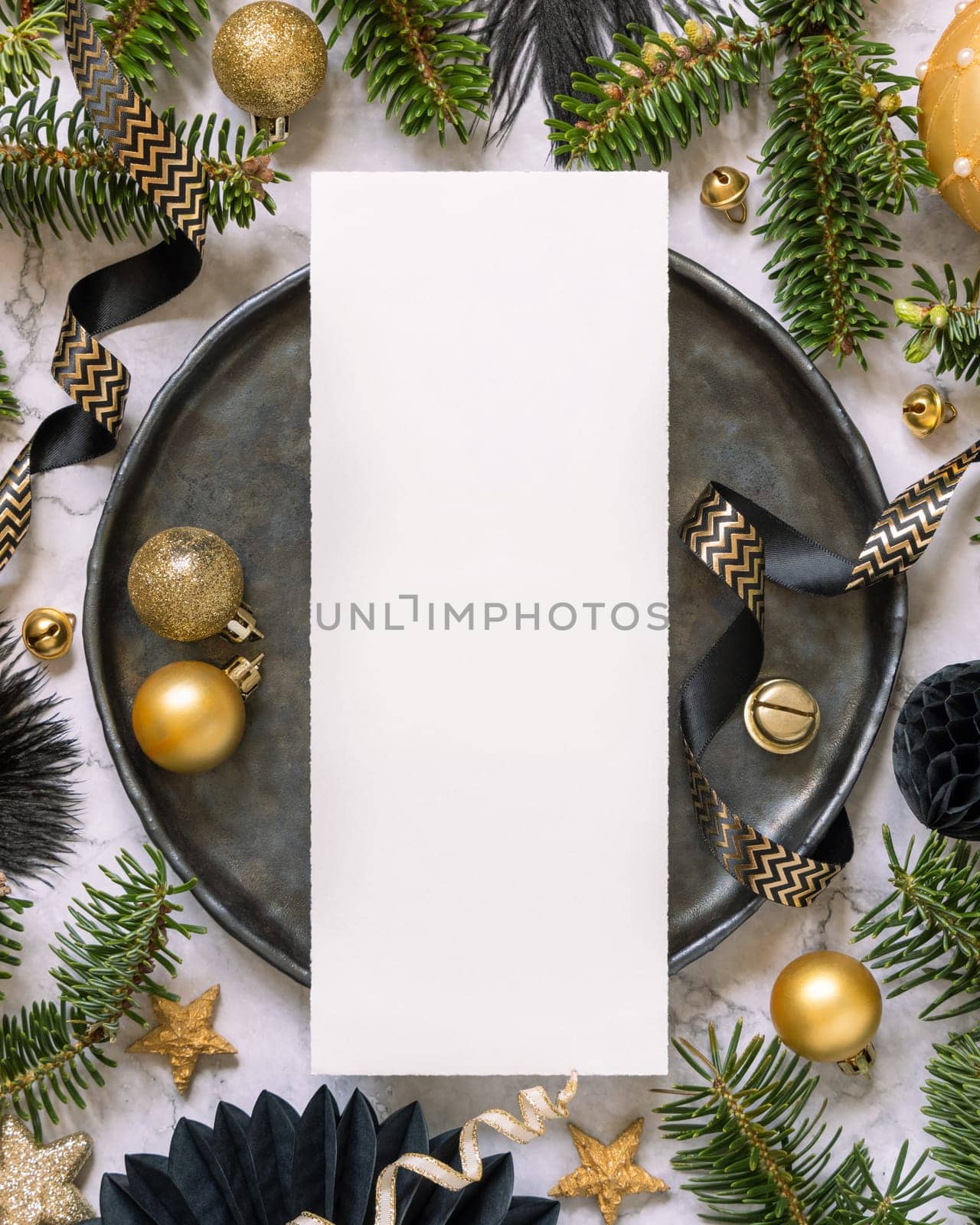 Black and golden Table setting with ornaments and fir tree branches, card mockup. Christmas or New Year menu on marble table flat lay, copy space. Winter season, restaurant holiday catering