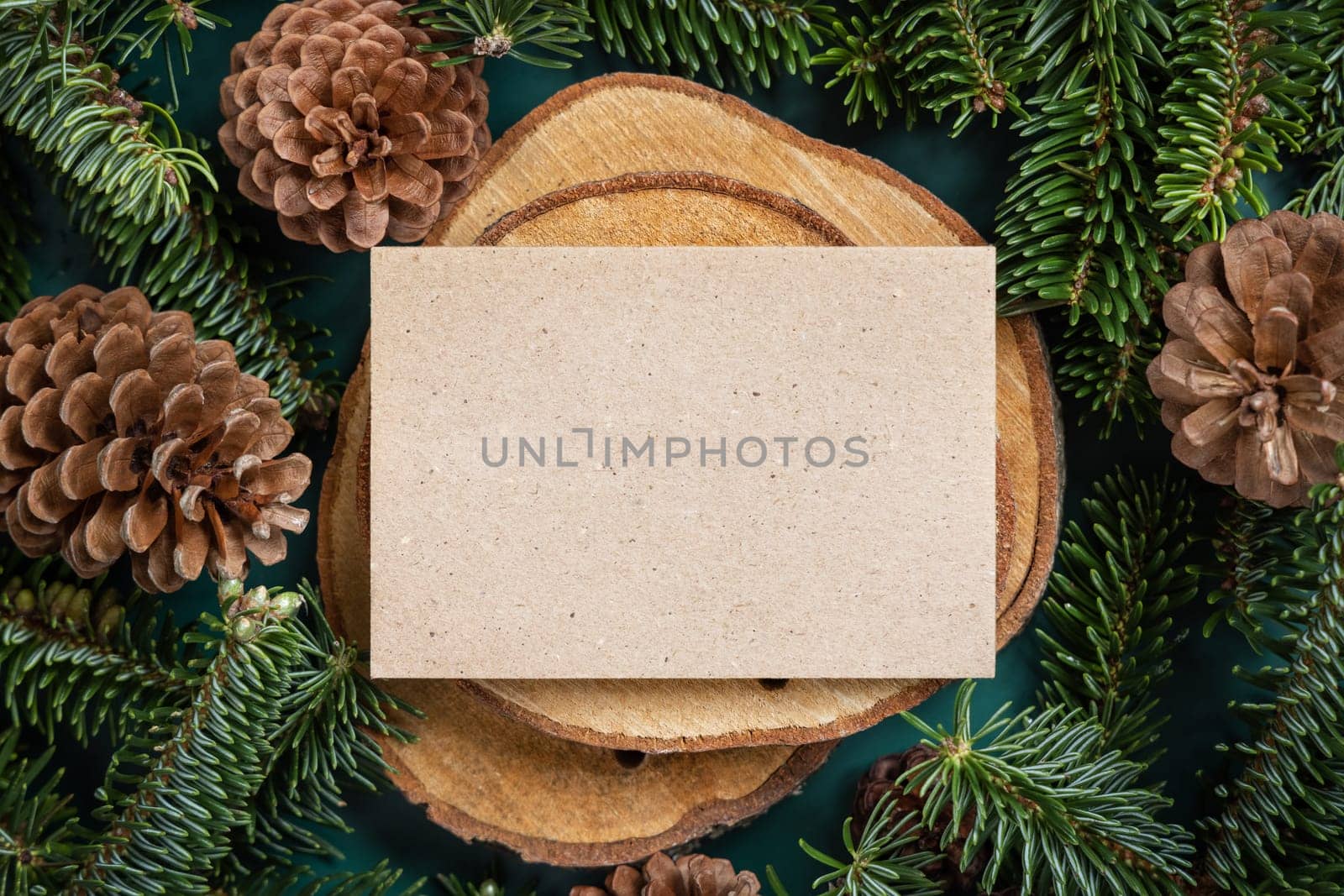 Horizontal blank card between fir branches and pine cones on green top view, mockup. Christmas or New Year greeting card template, Holiday winter composition
