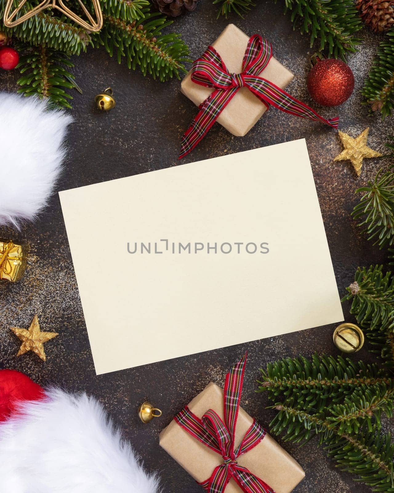 Paper card between Christmas decorations, wrapped gift boxes and green fir branches top view. Horizontal blank card mockup, flat lay, copy space. Christmas or New Year Holiday greeting card template