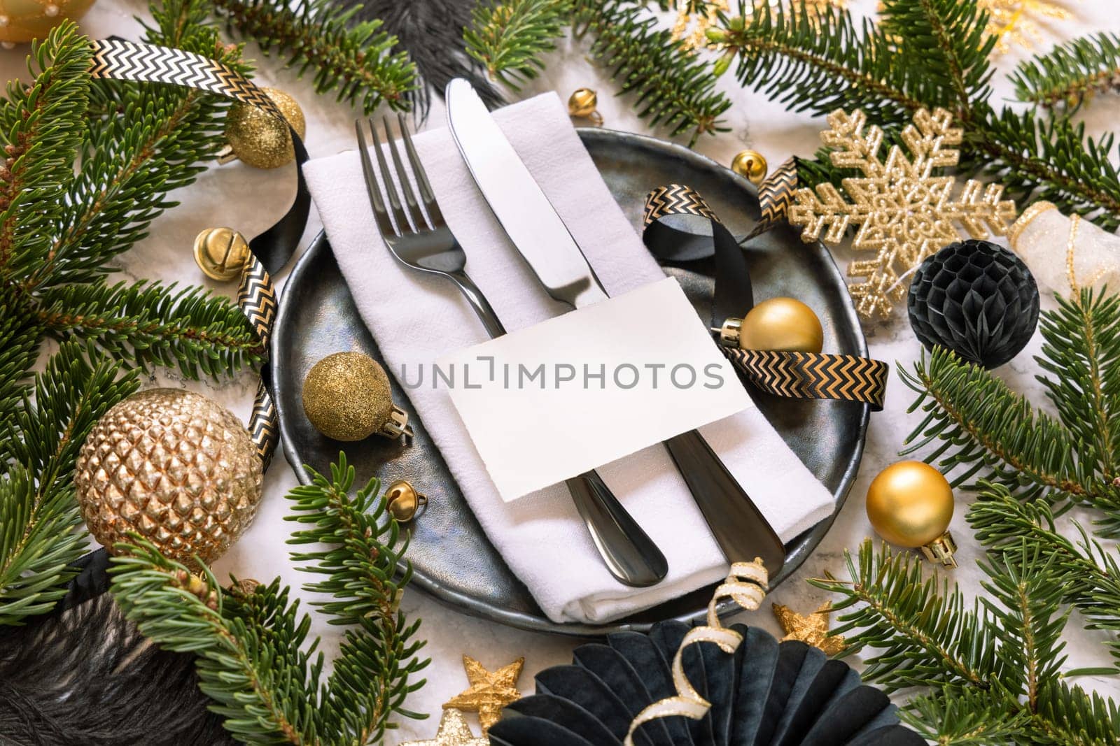 Black and golden Table setting with ornaments and fir tree branches close up, place card mockup. Christmas or New Year atmospheric composition, copy space.