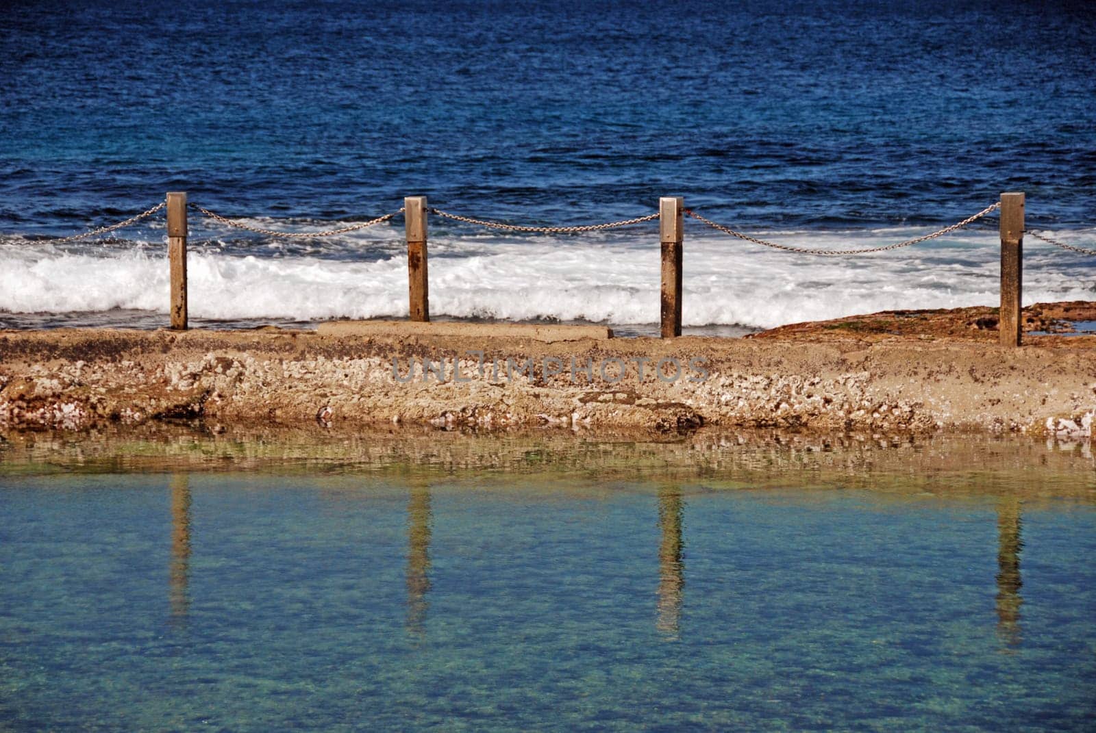 Reflections in ocean pool by coast with blue sea
