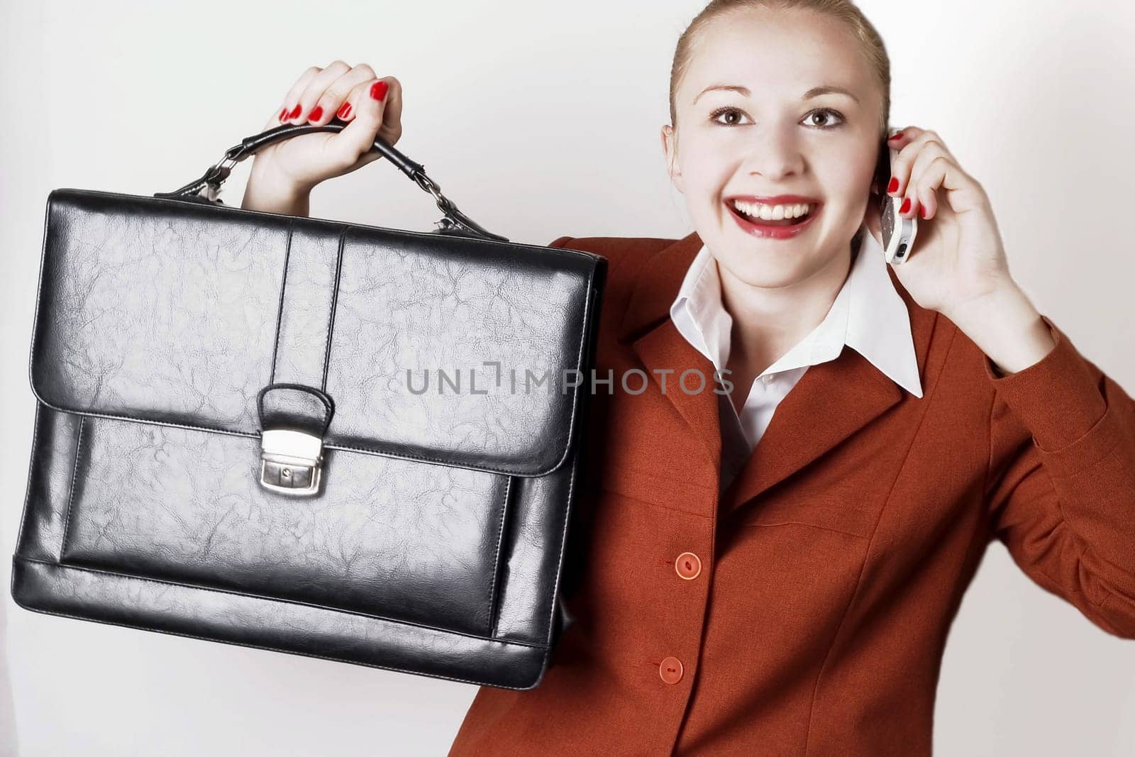 Businesswoman with suitcase wearing red suit working using  mobile phone.