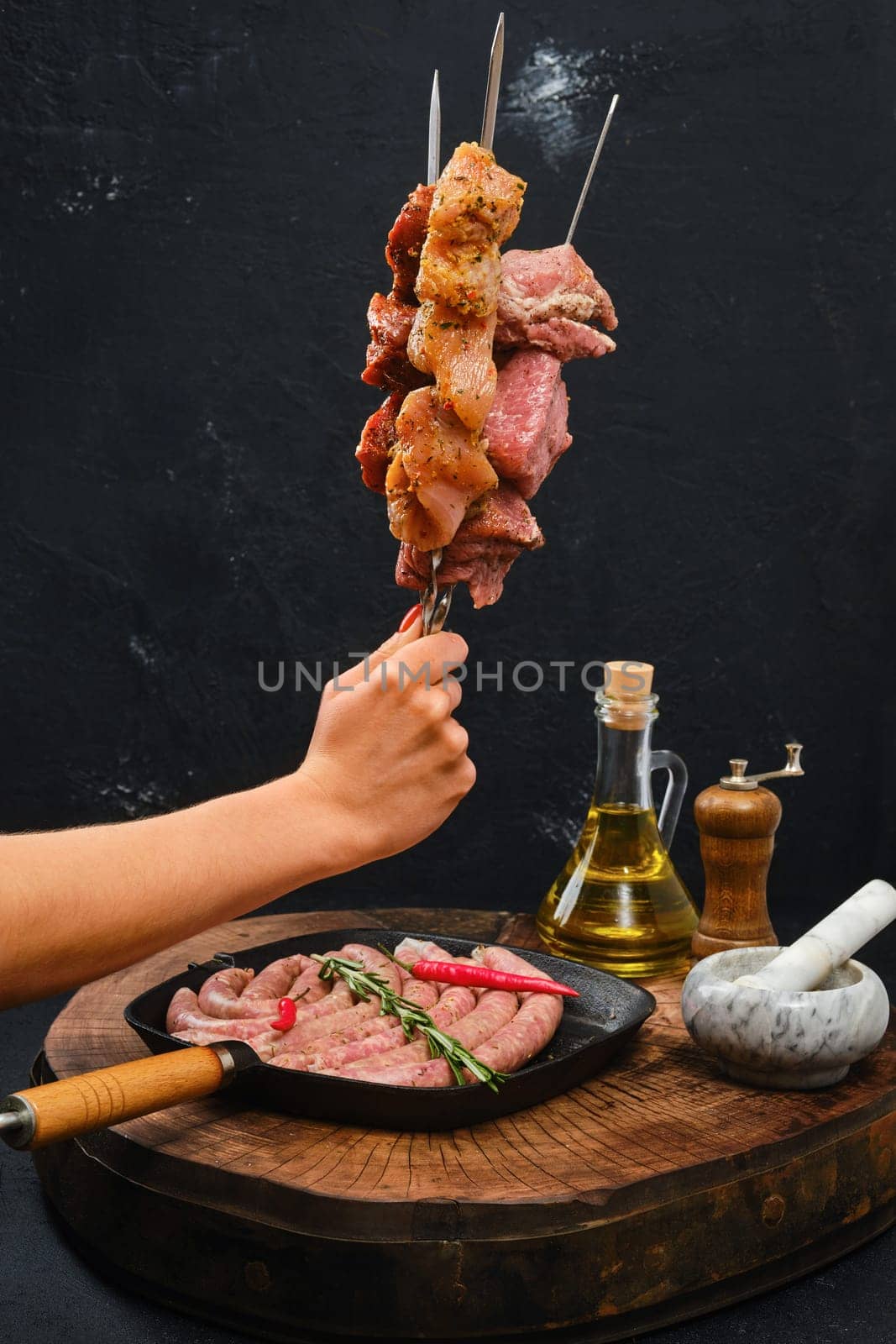 Hand holds skewers with marinated meat