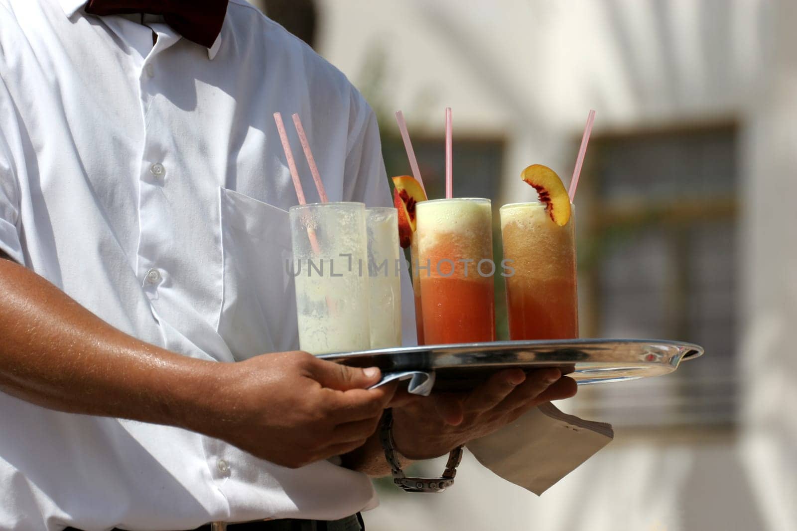 Waiter handling a salver with colorful cocktails.