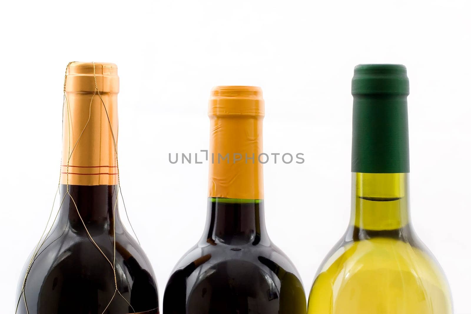 the top of three wine bottles on a white background