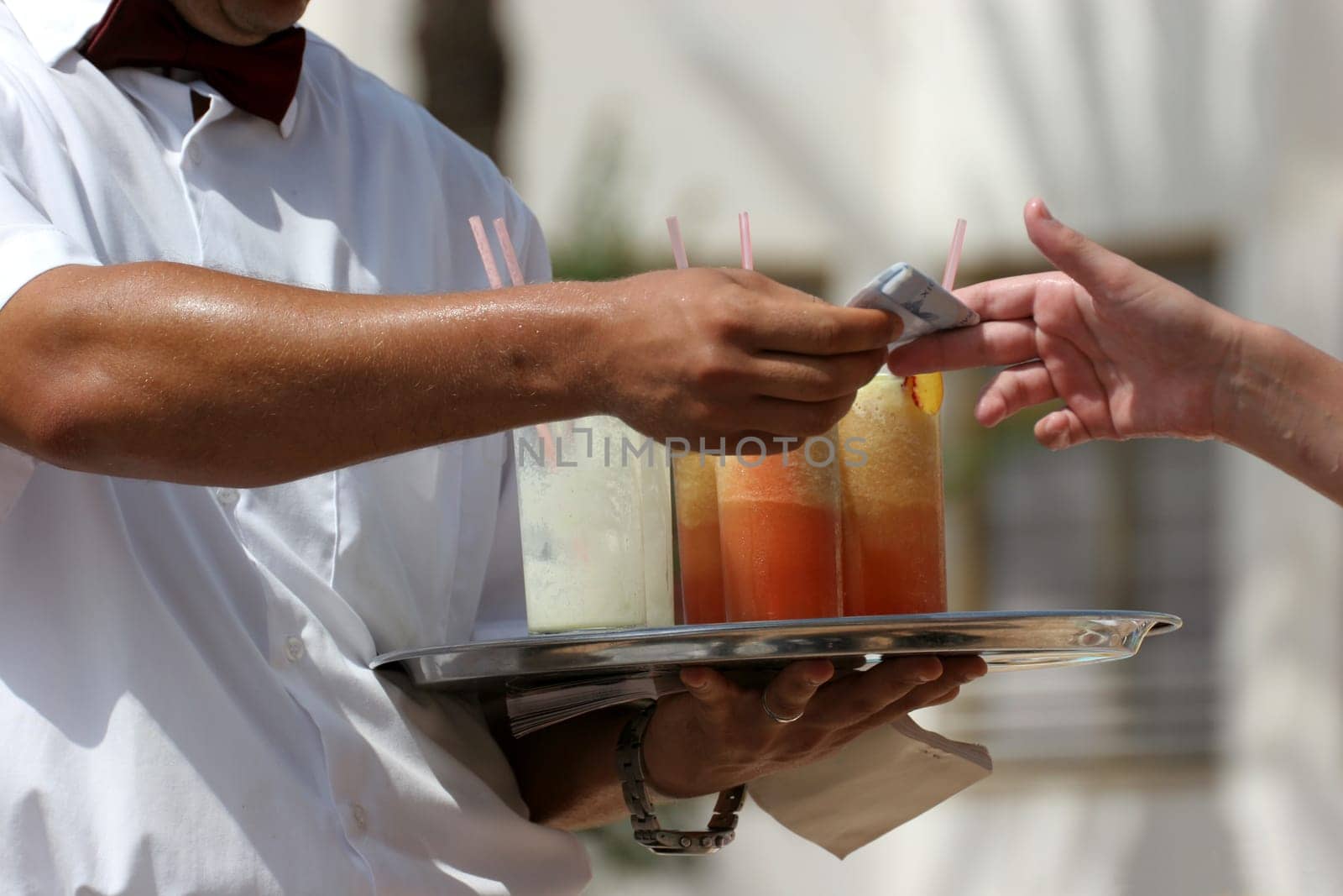 Waiter handling a salver with colorful cocktails.