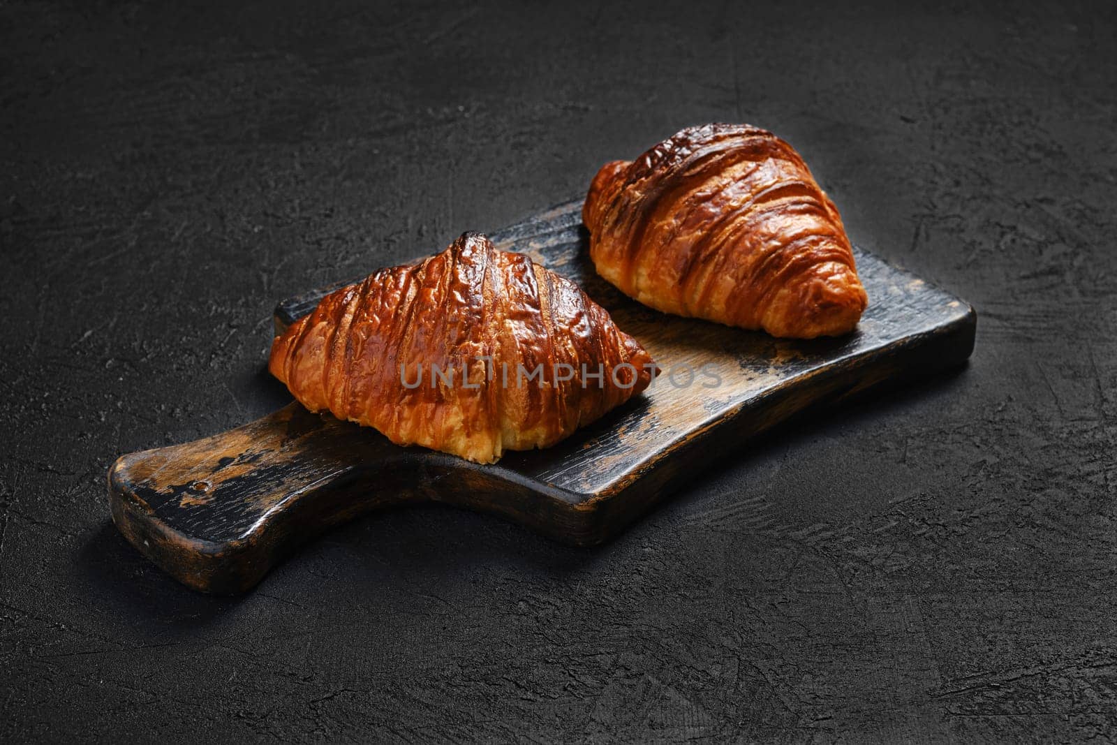 Crispy croissant on wooden serving board