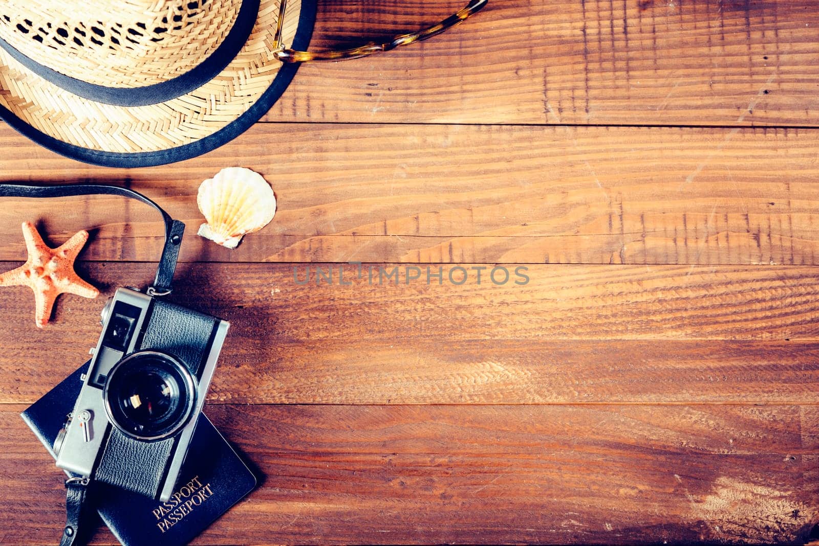 Vintage photo camera, retro hat, sunglasses and seashells border on wooden plank background. Summer holiday design with copyspace. Tropical traveling concept.