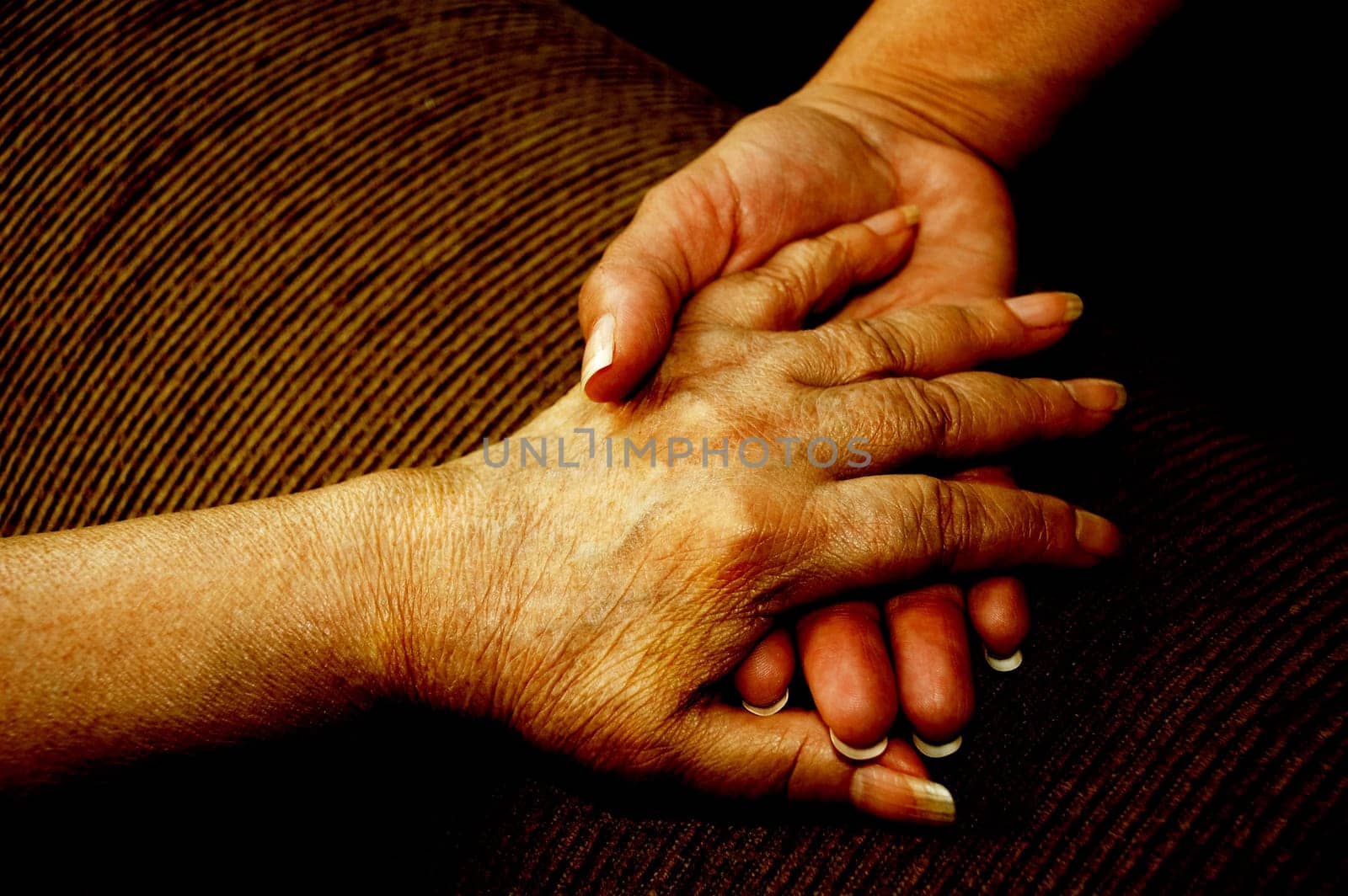 Mature hand holding aged hand in sign of unity
