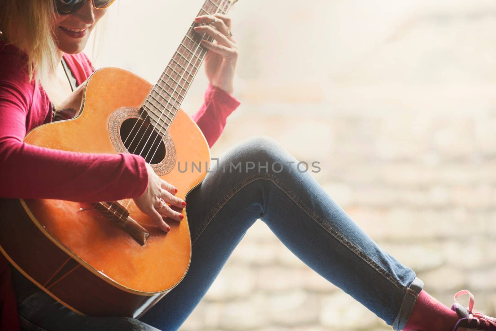 Closeup of young happy hipster woman plays the guitar with copyspace background. Summer fun and youth lifestyle concept.
