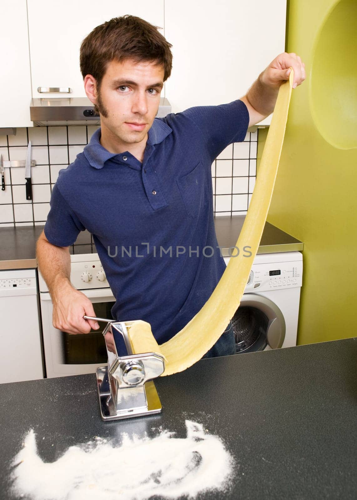 a young man making pasta at home in the kitchen