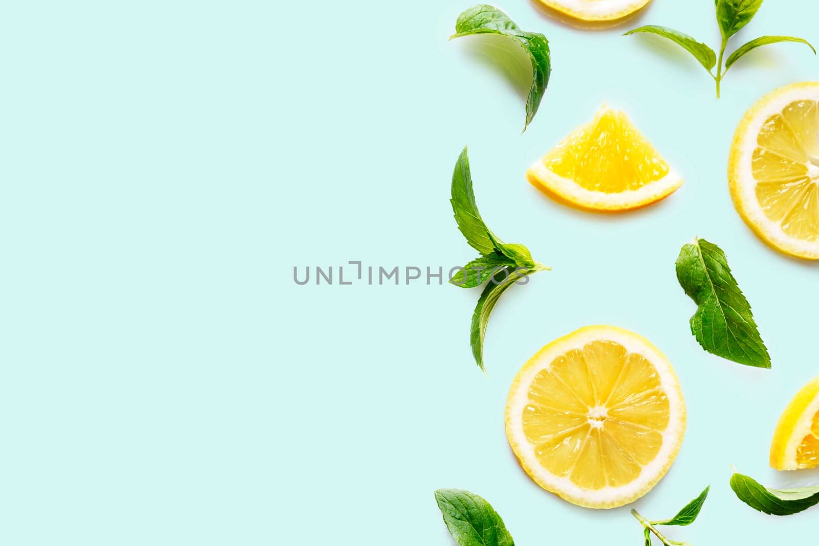 Top view of citrus slices and mint herbs frame on retro mint background with copyspace