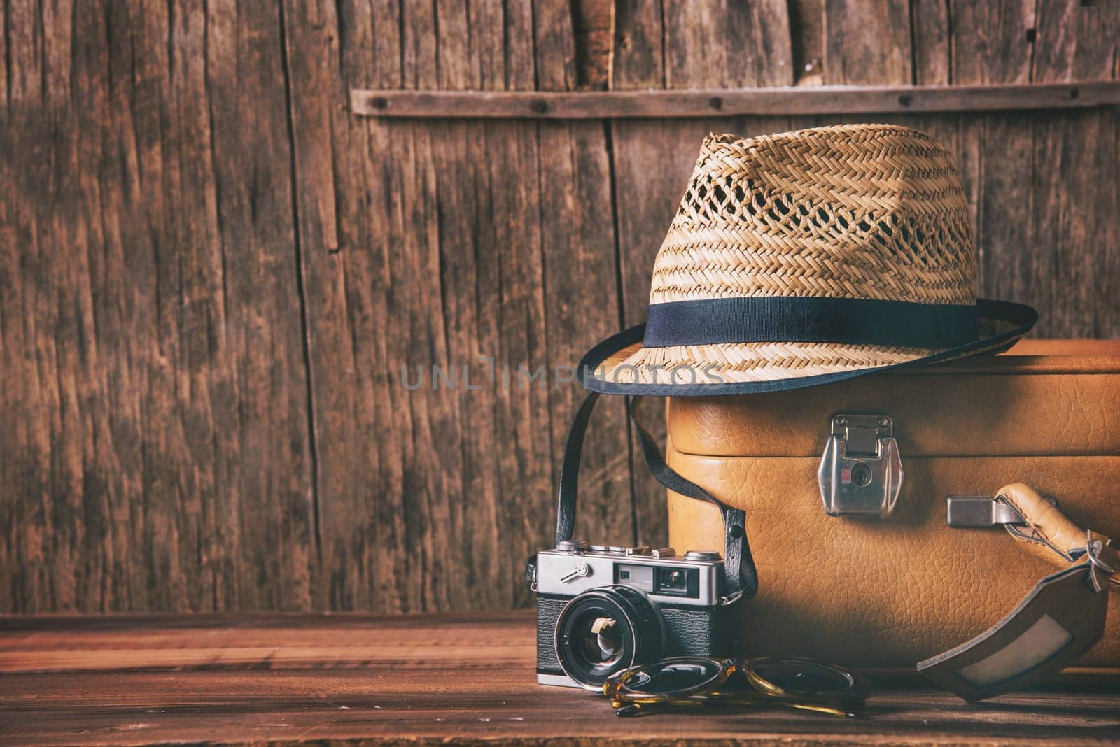 Vintage case, hipster hat, and retro camera on wooden background still life. Summer holiday vacation and adventure traveling concept with copyspace.