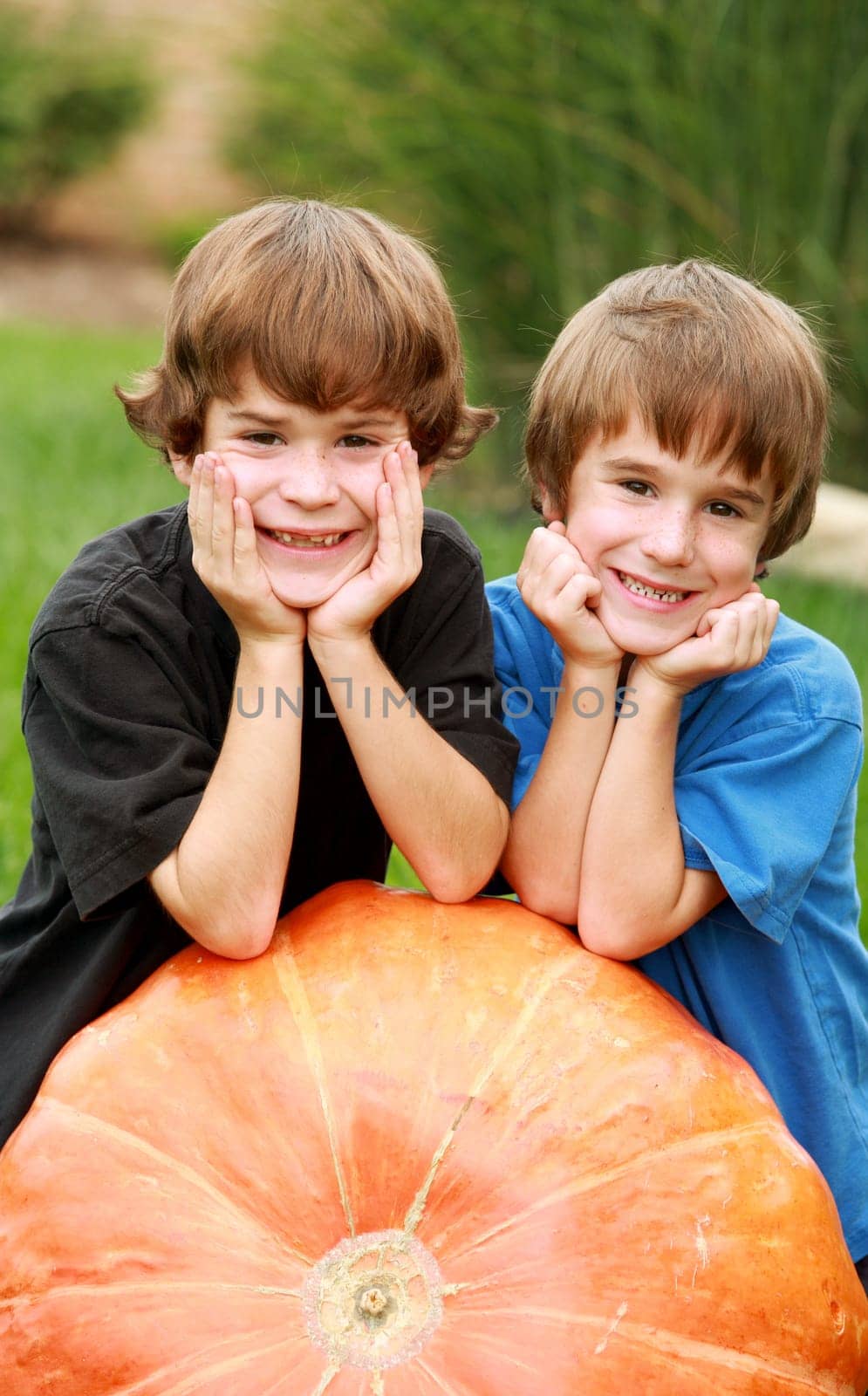 Two Boys Resting on a Huge Pumpkin