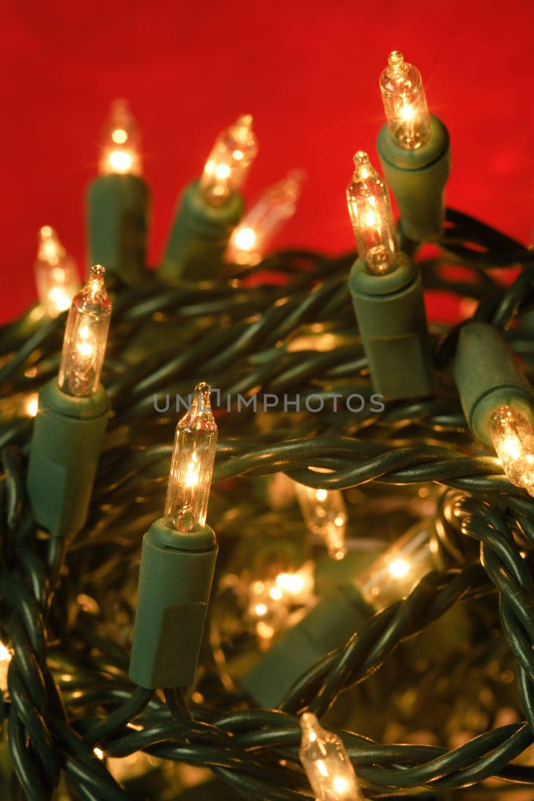 Shallow depth of field image of tangled illuminated Christmas lights.  Focus is on the middle bulb.