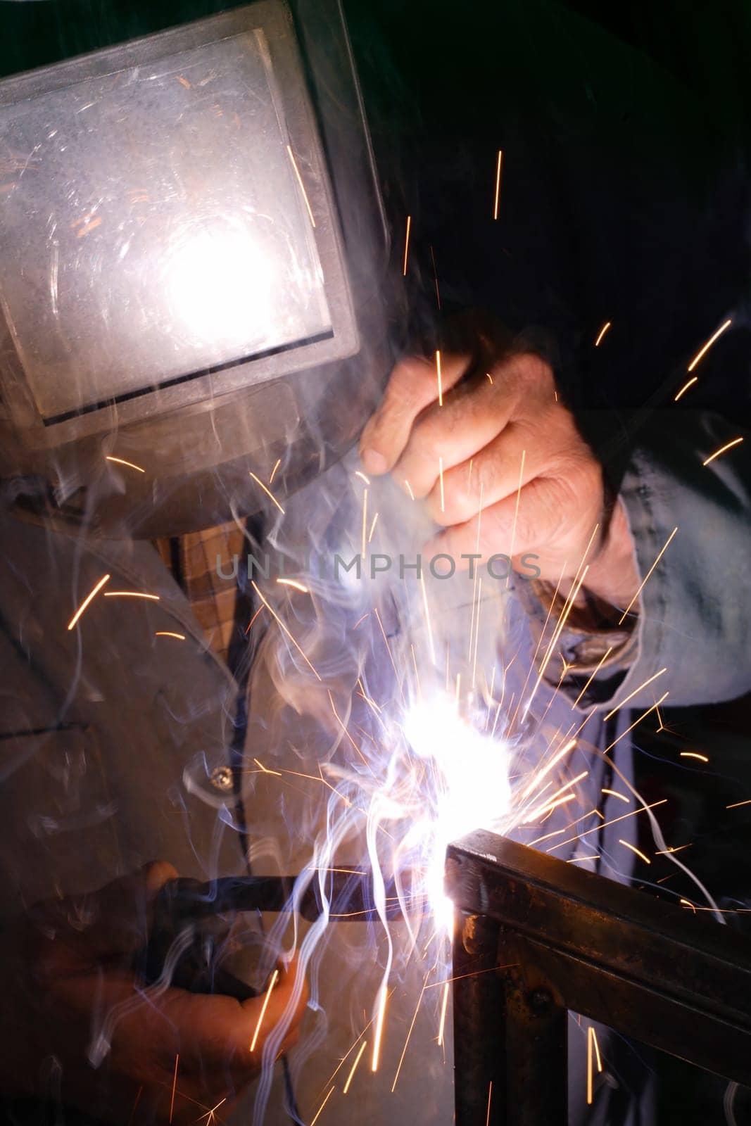 A welder using a mig torch to attach two pieces of metal.