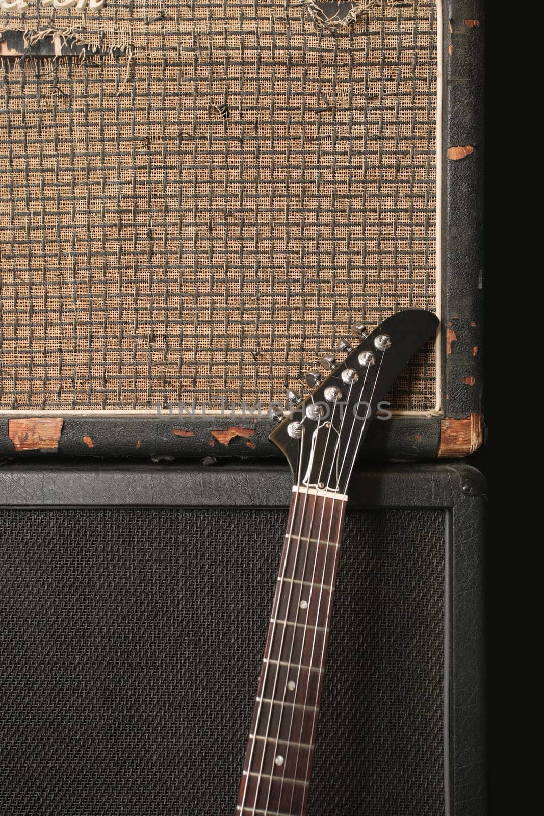 An electric guitar leaning up against an old vintage amplifier.
