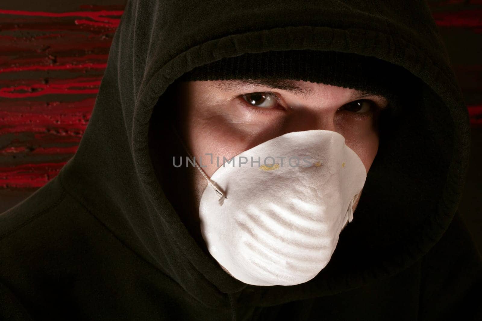 A male lurking in the shadows wearing a mask.