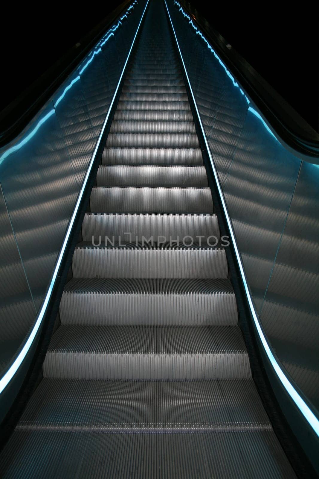 An escalator going up with colored stripes on both sides