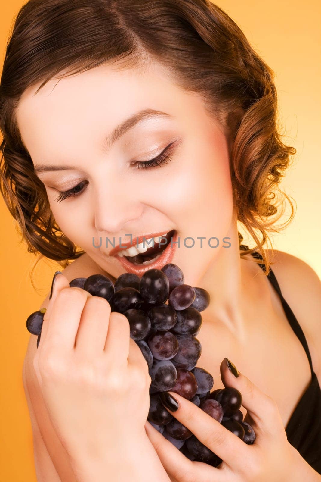a glamorous girl holding some grapes in her hand