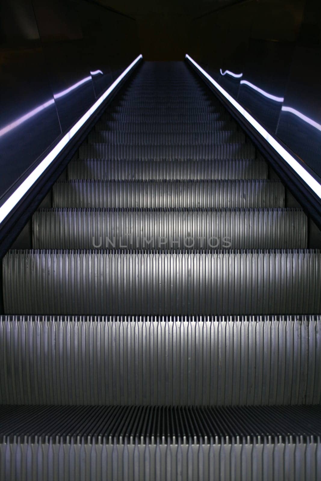 An escalator going up with colored stripes on both sides