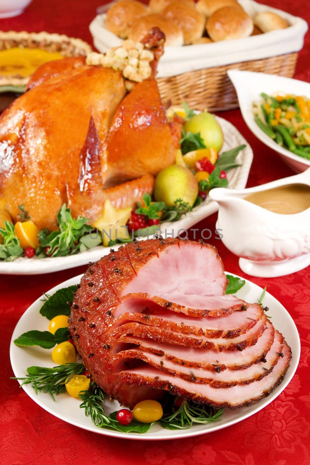Holiday dinner with baked ham, roast turkey, pumpkin pie, gravy, dinner rolls, green beans salad