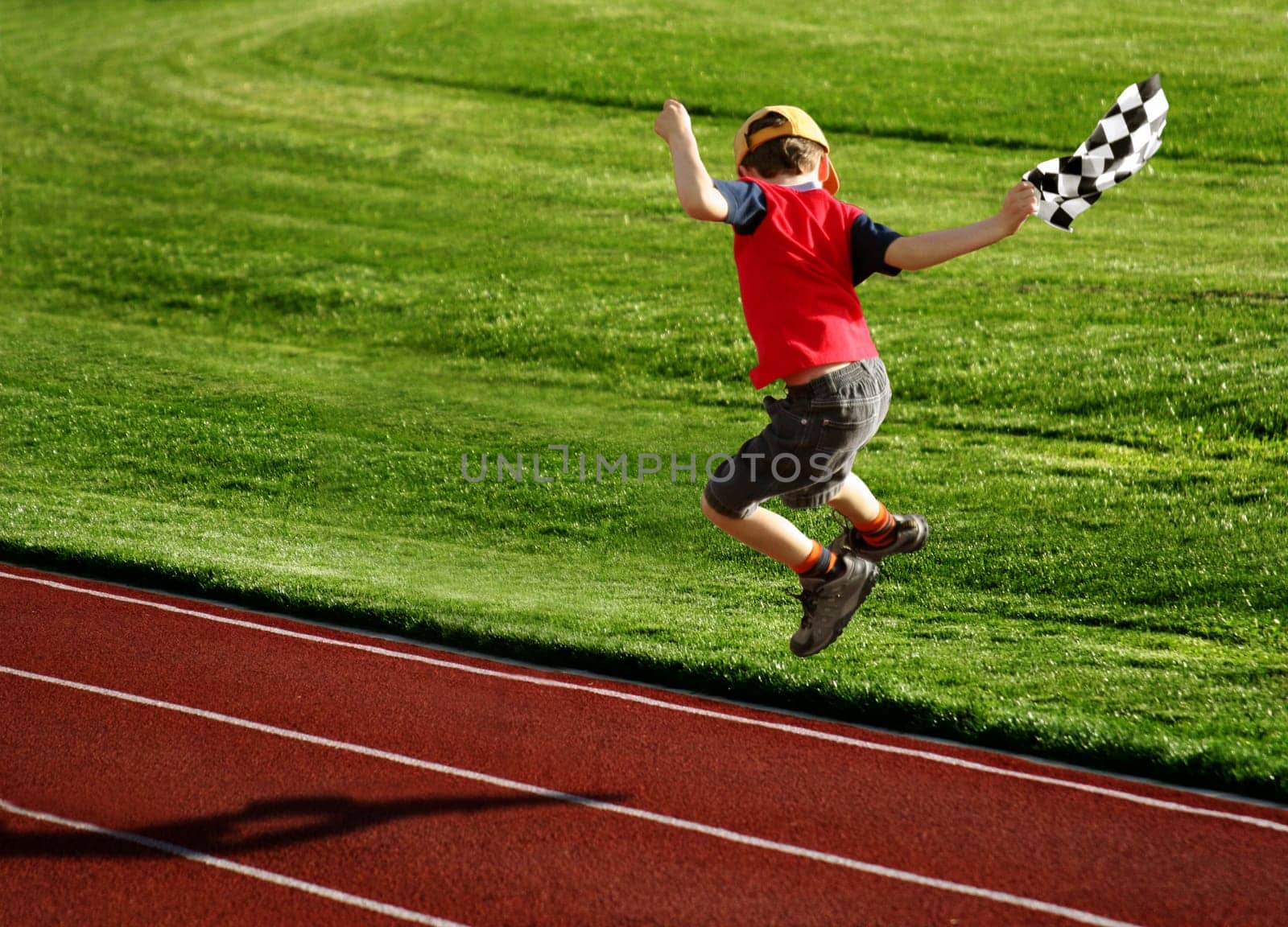 Boy with a checked flag jumping on a racetrack