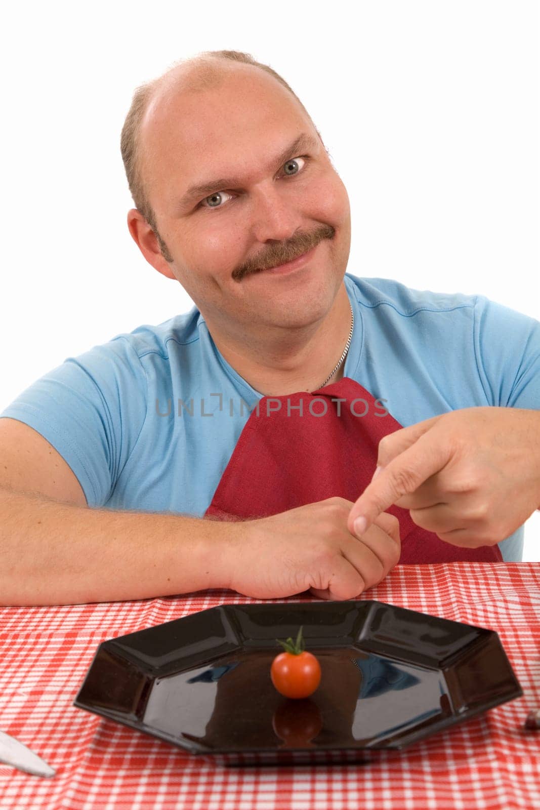 Mature man pointing at his plate where only one tomato is placed