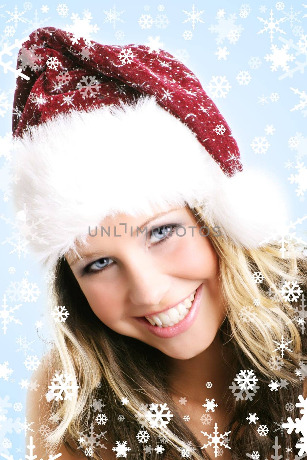 winter portrait of a young smiling woman with a christmas cap and snowflakes